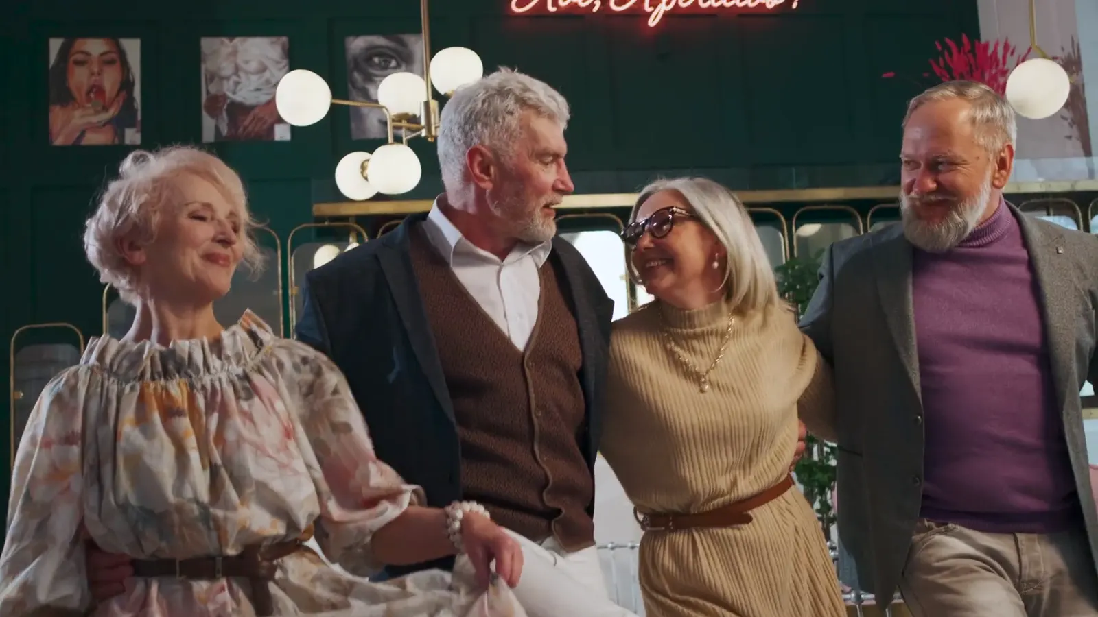 Four old friends arm in arm, laughing, at a reunion